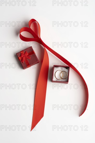 From above, a romantic Valentine's Day setup featuring a red ribbon arranged in a heart shape, with