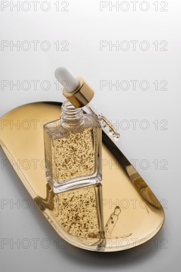 A high-end face serum enriched with gold flakes, presented in a stylish glass bottle with a