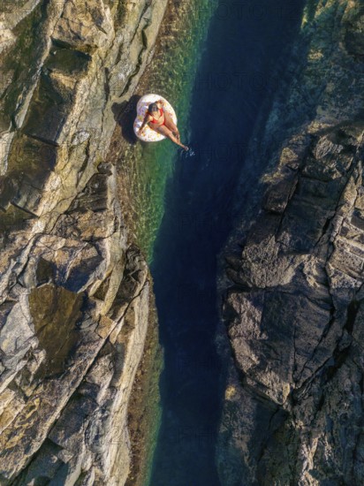 Top view of an unrecognizable woman floating on an inflatable in the clear, waters of a natural