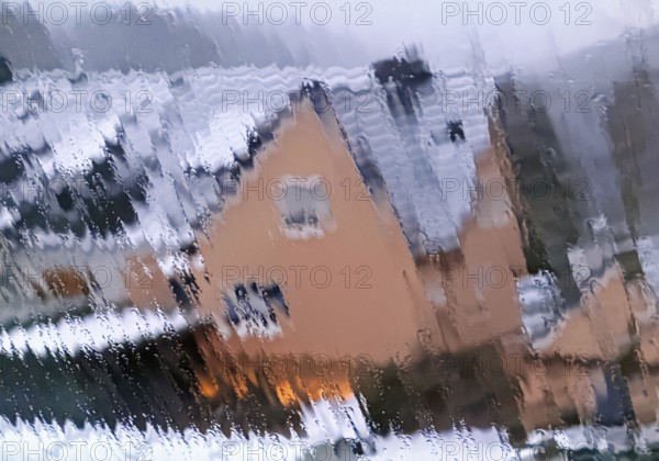 Continuous sleet on a window pane with an unclear view of a house in winter, Witten, North