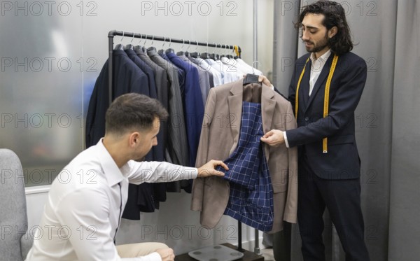 A tailor assists a customer in selecting a suit in modern store. The tailor shows the inner lining