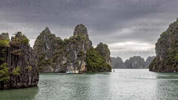 Limestone cliffs and small boats on calm waters under a cloudy sky, The landscape and islands of