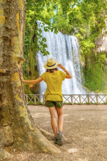 A tourist woman with a hat looking at La Caprichosa waterfall in the Monasterio de Piedra Natural