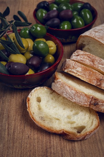 A mixture of olives, varieties of Halkidiki, Verdi giganti and Kalamata, in a bowl, with sliced