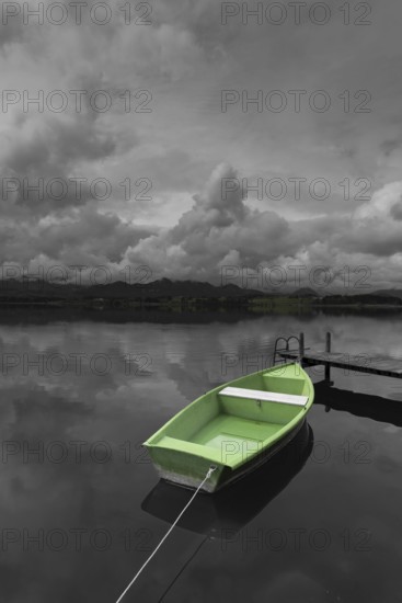 Storm clouds at sunset, a green rowing boat lashed to the wooden jetty, Hopfensee, Hopfen am See,