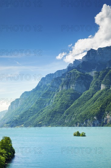 Sunny view over Lake Walen with the small chive island in the turquoise water and mountain range