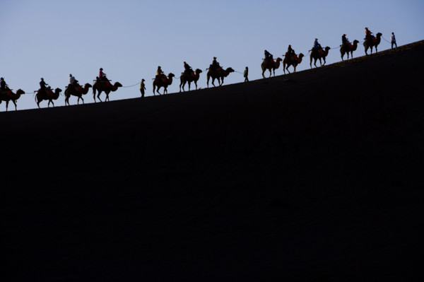 A Group of People Riding Camels in the Desert