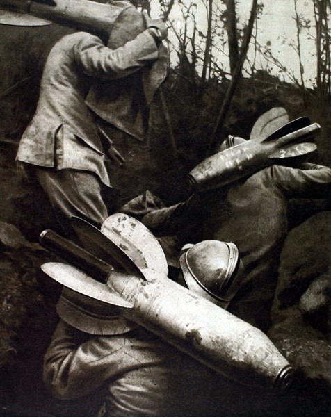 In a forward trench, men carrying aerial torpedos on their back