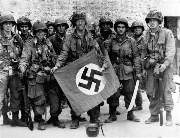 Des parachutistes américains posent avec un drapeau nazi capturé, 1944