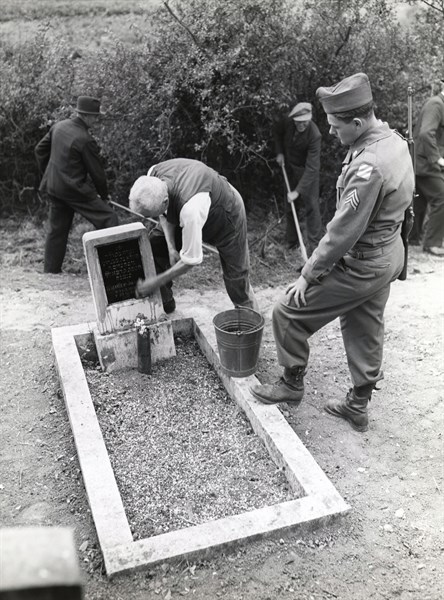 A former member of the Nazi party cleans a tombstone in the Jewish cemetery of Bergheim (July 28,1945)
