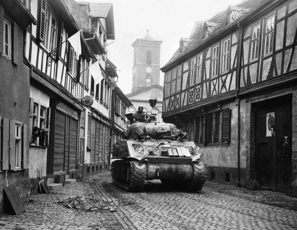 Char américain passant avec fracas sous les drapeaux blancs à Hanau, en Allemagne. 
(28 mars 1945)