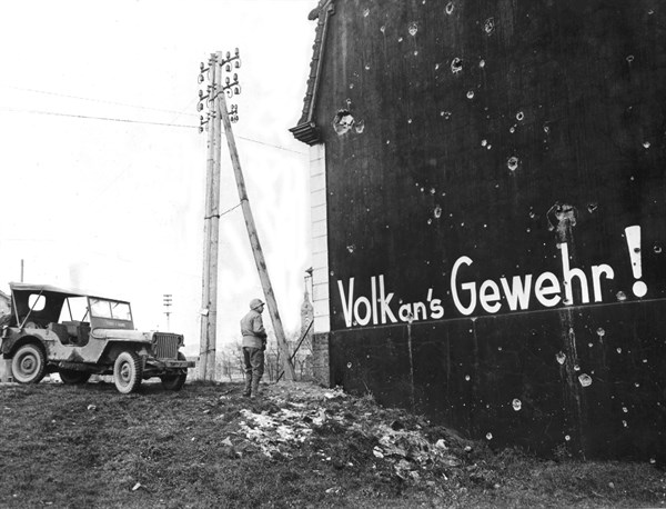 Soldat américain découvrant un slogan qui enjoigne les Allemands à prendre les armes. (Décembre 1944)