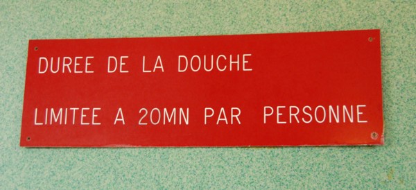 Ein Hinweisschild mit der Aufschrift: "Duree de la douche limitee a 20...