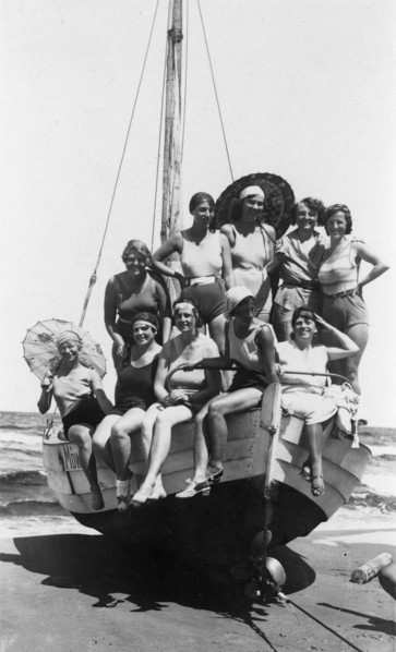 Eine Badegesellschaft von Frauen und Mädchen in Badekleidung posiert am Strand der Ostsee auf einem