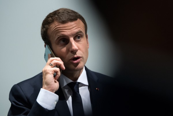 Emmanuel Macron talks on his telephone as he walks along a corridor in the exposition halls in Hamburg