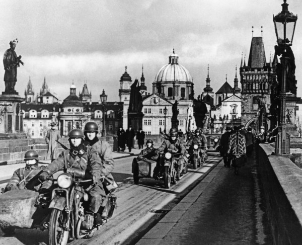Die deutsche Wehrmacht marschiert in Prag ein. Die bewaffneten Soldaten fahren mit Motorrädern über