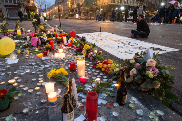 A man mourns next to a banner that reads 'Je suis Bruxelles Ik ben Brussel' (lit. I am Brussels) in