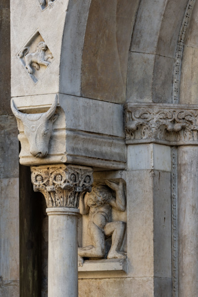 Fidenza, duomo (Cathedral of San Donnino), façade, left portal, prothyrum: telamon, capital and