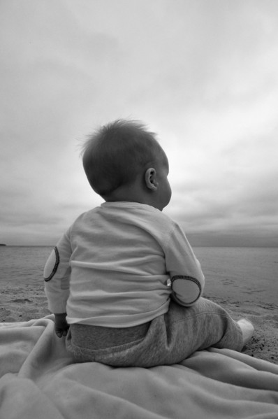 Baby Boy Sitting on Beach, Rear View