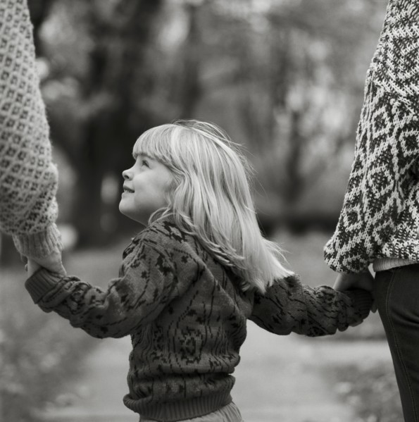 Young Blonde Girl Holding Parents' Hands
