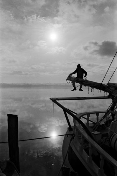 Sailor Sitting on Pole on Sailboat