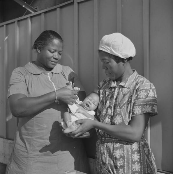 Nurse Examining Infant with Mother and Child Receiving Prenatal and Postnatal Care, Okeechobee Migratory Labor Camp, Belle Glade, Florida, USA, Marion Post Wolcott for Farm Security Administration, Ju...