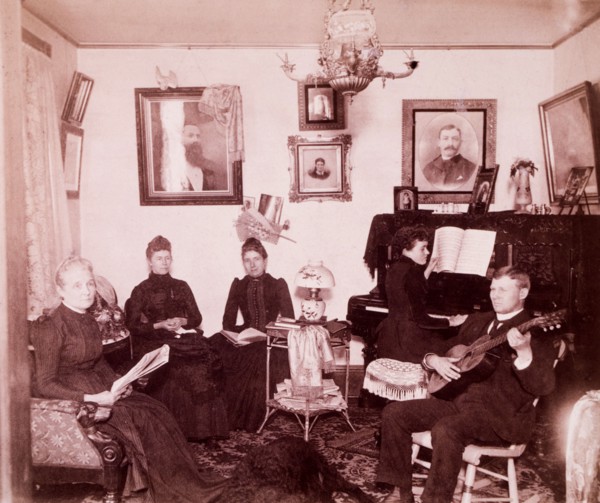 Family Sitting in Parlor While One Person Plays Piano and One Plays Guitar, USA, circa 1890