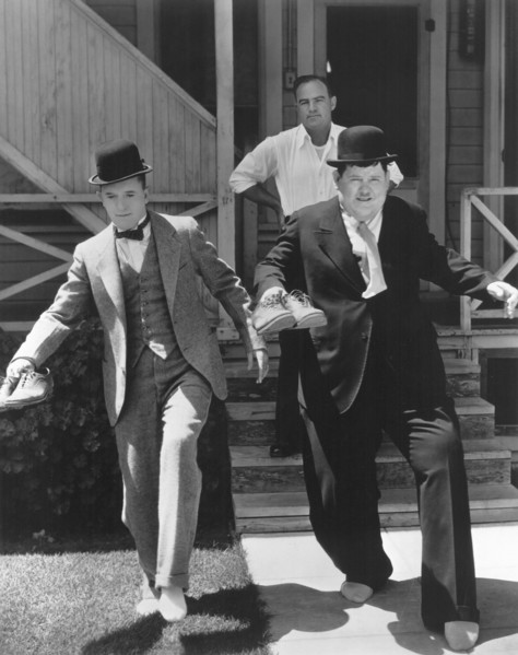 Stan Laurel and Oliver Hardy trying to Sneak Away from Producer Hal Roach, circa 1930's