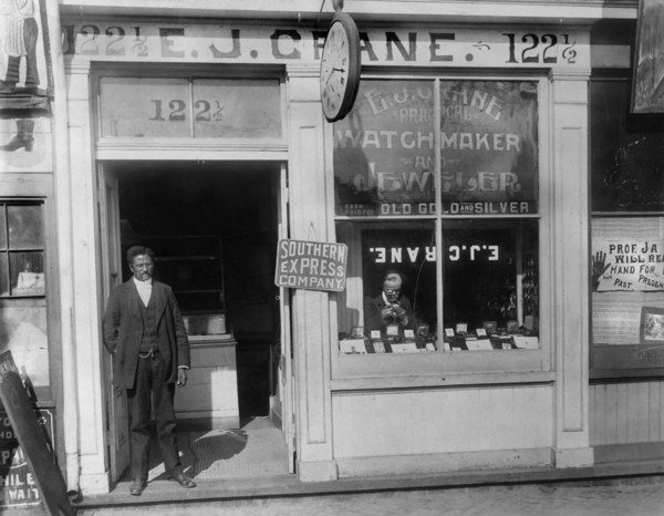 Man Working in Window and Man Standing in Doorway, E.J. Crane Watchmaker and Jewelry Store, Richmond, Virginia, USA, 1900