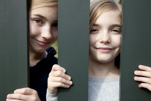 Two Smiling Girls Behind Fence