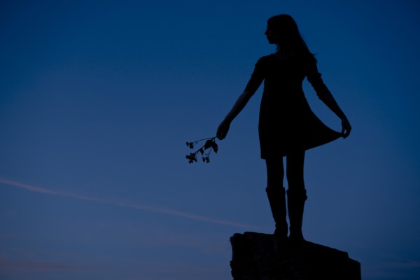 Girl Standing on Rock Holding Flowers, Silhouette
