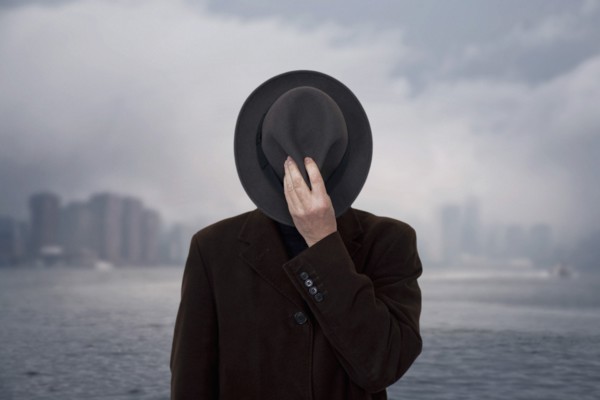 Man with Hat Covering his Face against Cloudy Sky