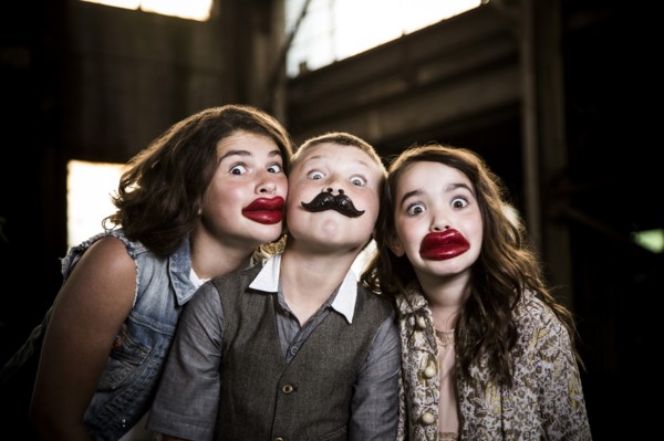 Two Wide-Eyed Girls and Boy Wearing Wax Lips and Making Silly Faces in Abandoned Warehouse