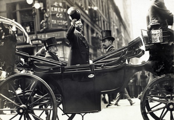 Theodore Roosevelt Standing in Carriage with his Hat Tipped while New York City Mayor William Gaynor and Cornelius Vanderbilt remain seated during his homecoming Reception after his trip abroad, New Y...