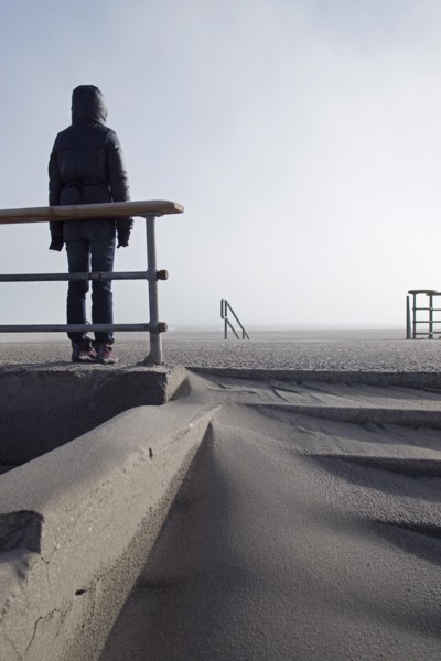 Rear View of Hooded Person Standing on Empty Beach