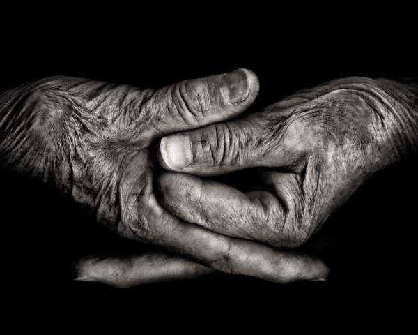 Two Wrinkled Hands against Black Background