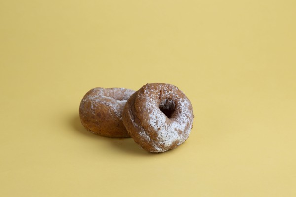 Two Doughnuts with Powdered Sugar on Yellow Background