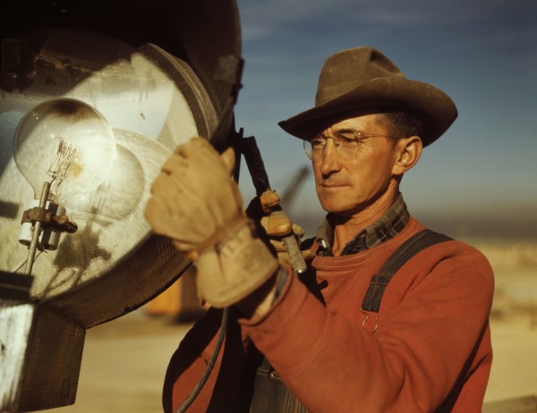 Man servicing floodlight at new construction of steel plant being built to aid war effort of steel production