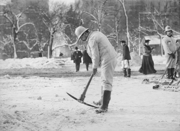 Man clearing street with pickaxe after snow storm