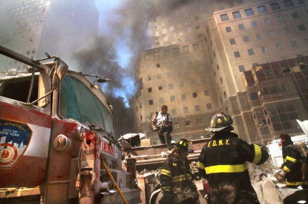 New York City Fire Fighters amid debris with smoldering ruins in background