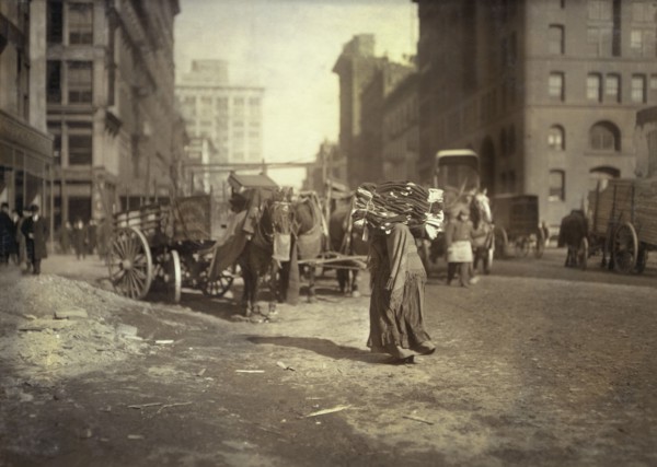 Woman carrying heavy load of clothes on her shoulders