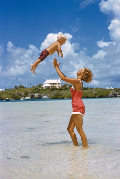 Woman playfully tossing Young Boy in Air at Beach
