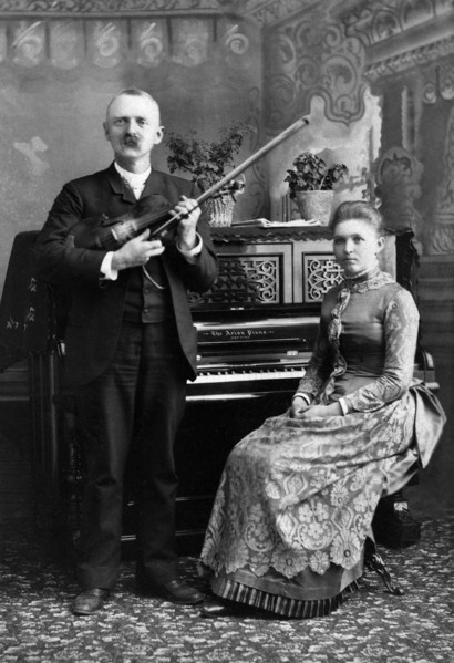 Portrait of Man holding Violin and Woman seated at Piano