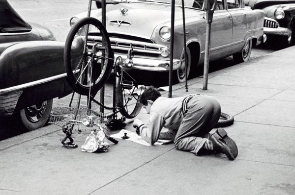 Man fixing bicycle on sidewalk