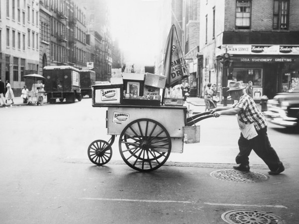 Man pushing hot dog cart across street