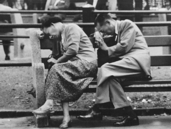 Woman and man napping on park bench