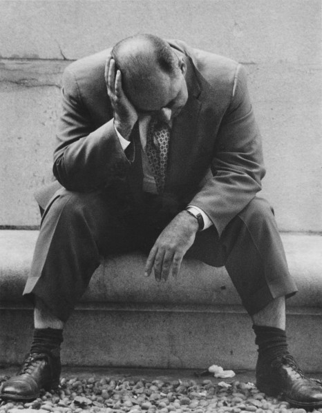 Man sitting with head resting on hand