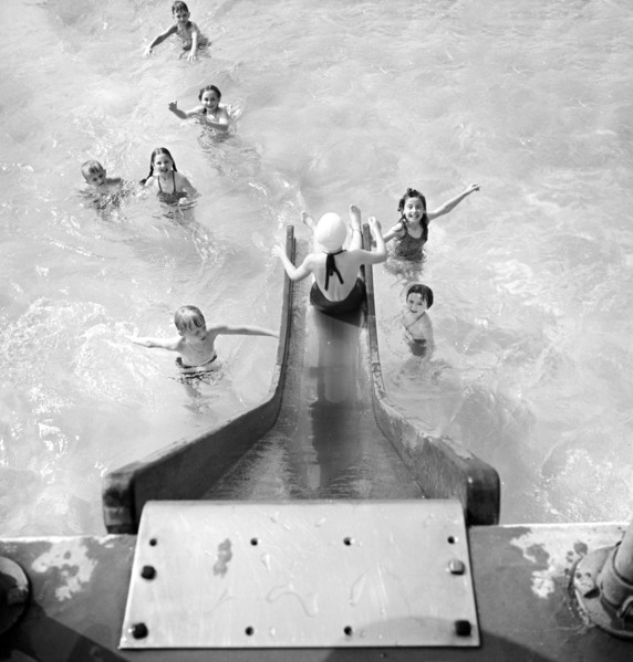 High angle view  of children entering swimming pool from water slide, Greenbelt, Maryland, USA,