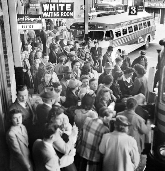 Crowded bus terminal with "White Waiting Room" sign in foreground and "Colored Waiting Room" in