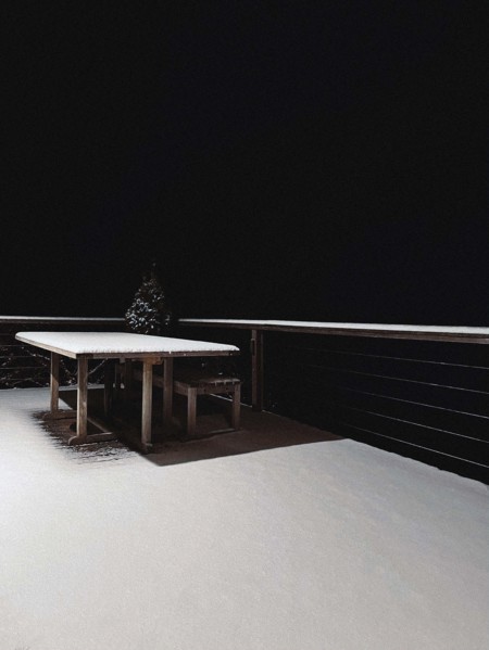 Snow-covered wood table and patio at night